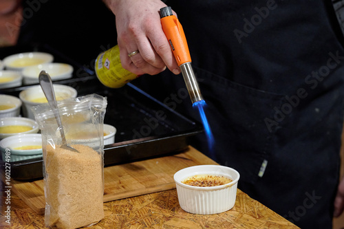 Obraz na plátně Chef caramelizing crème brûlée dessert with culinary torch