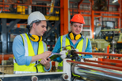 Engineers actively monitor the production line in a metal sheet factory. Engineers are checking the operation of Metal Sheet machines in factory.