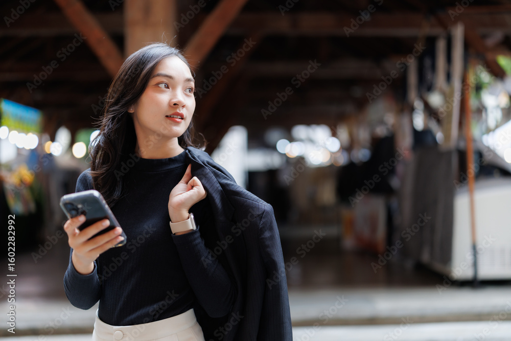 Obraz premium Businesswoman using smartphone walking in a market hall