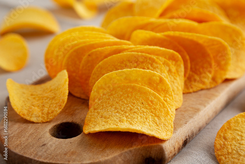 Bacon flavoured potato chips on a wooden board, side view. Close-up.