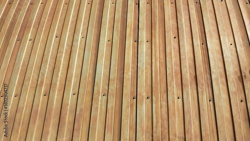A close-up view of smooth, parallel wooden planks with a natural light brown finish, showcasing uniform grain patterns and evenly spaced screws