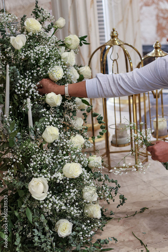Canvastavla Floral designer arranging large vertical installations of white roses, baby’s breath, and greenery near golden decorative birdcages