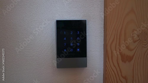 Closeup of illuminated digital keypad security lock mounted on wall Modern touch access panel for home or office entry Safety technology and electronic smart lock system in use indoors with wooden