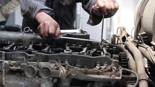 Mechanic man fixing truck engine with tools in professional service center.