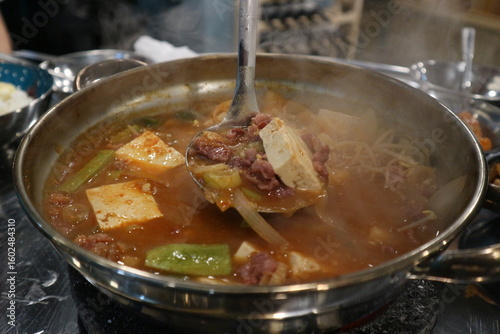 Korean Barbecue Grill Setup with Fresh Beef, Side Dishes, and Vegetables at Traditional Restaurant Table