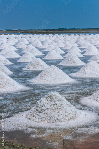 Pyramids of sea salt ready to be harvested in a salt farm at sunrise. Used as a seasoning in food, cosmetics and for food preservation.