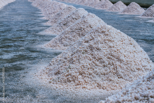 Pyramids of sea salt ready to be harvested in a salt farm at sunrise. Used as a seasoning in food, cosmetics and for food preservation.