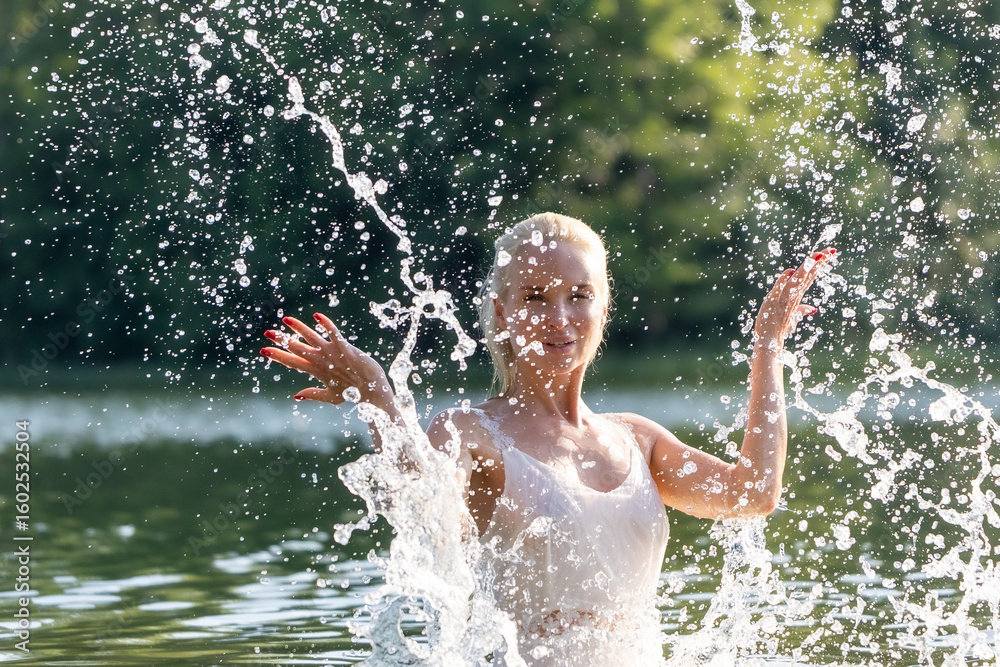 Fototapeta premium Woman in White Dress Playing with Water Splash Outdoors
