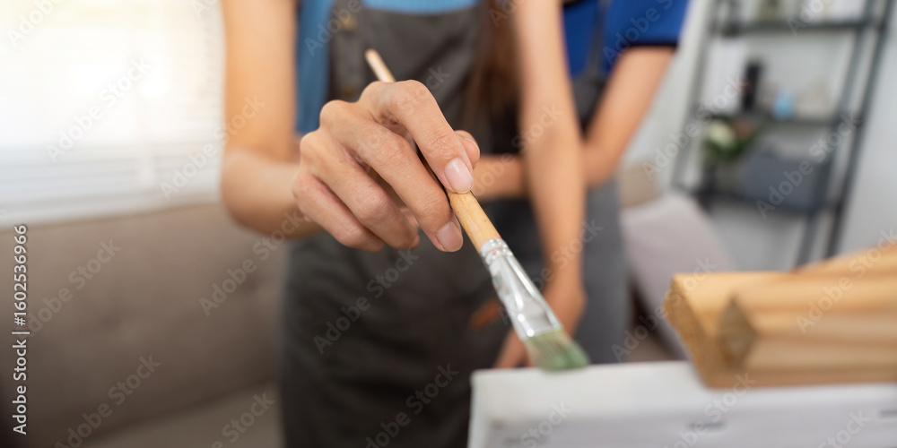 Obraz premium Close-up of a lesbian artist painting with a brush in a cozy home