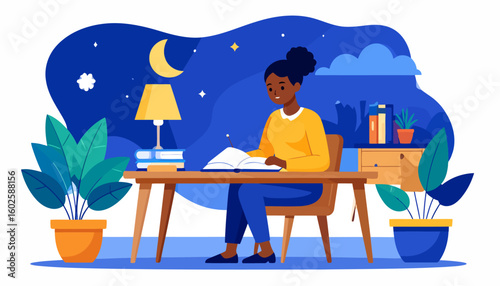 Smiling Black woman with a hair bun in a yellow sweater, studying at her desk at night.