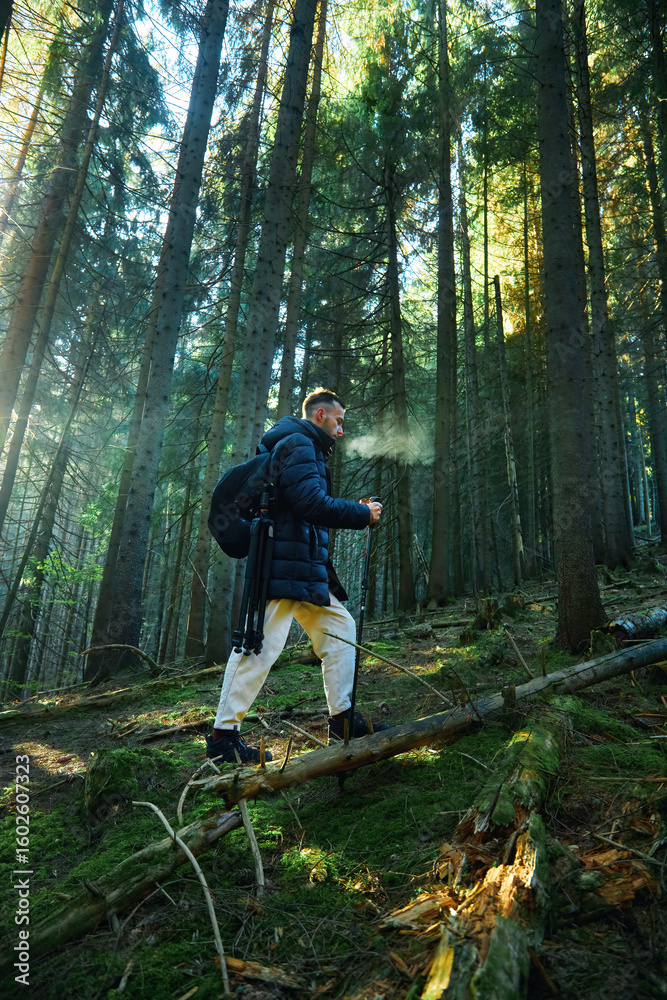 Obraz premium Man hiker with backpack walking through forest in Carpathian mountains enjoying river view.