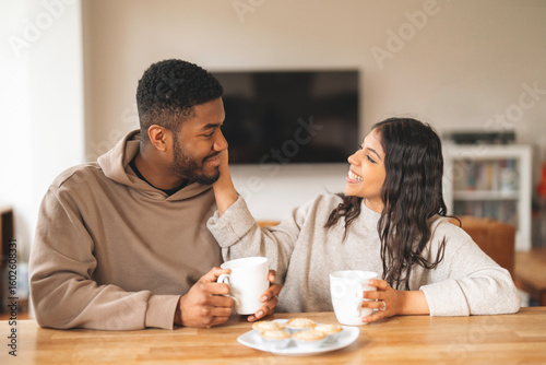 Smiling couple enjoying coffee and cookies in a cozy living room during a relaxed afternoon together