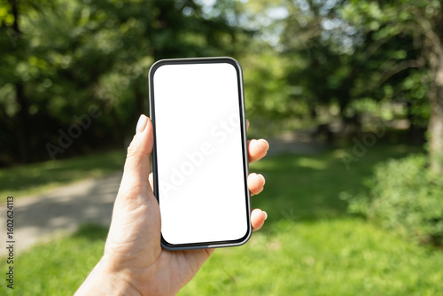 Womans hands with smartphone in outdoor green setting. Check apps, focused on device, chatting, performance data. Voice assistant. Fitness progress on app. Space for design on white blank screen