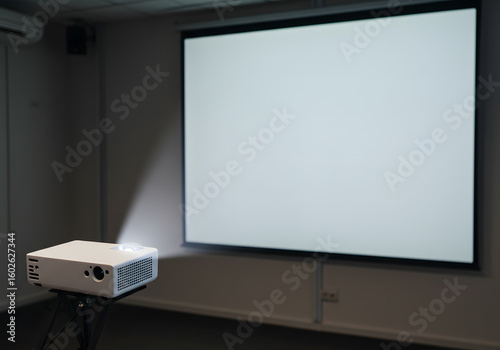 Projector projecting onto blank screen in a dimly lit room