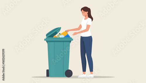 Smiling young woman with a ponytail throwing recyclable waste into a green wheeled bin.