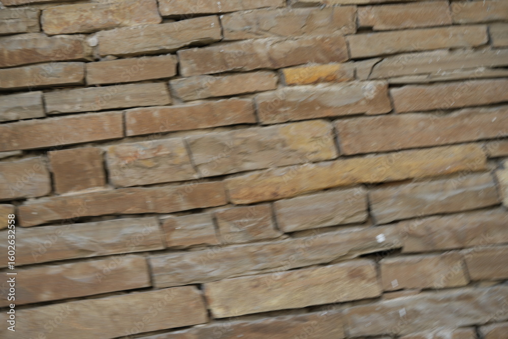 Fototapeta premium Natural sandstone wall texture with irregular horizontal layers and warm earthy tones. Rough stacked stone surface ideal for architectural backgrounds and 3D materials.