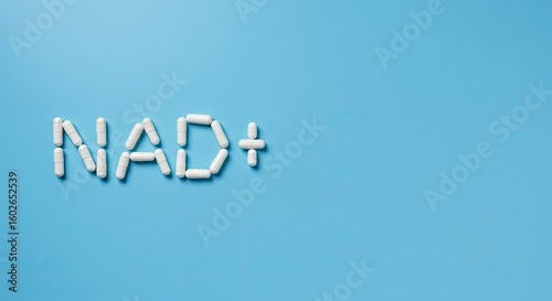 NAD+ sign made from white supplement capsules with bottle on blue background with copy space. Nicotinamide adenine dinucleotide for anti-aging and longevity.