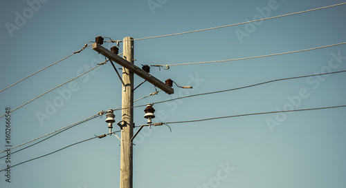 An aged wooden utility pole against a serene blue sky backdrop outdoors