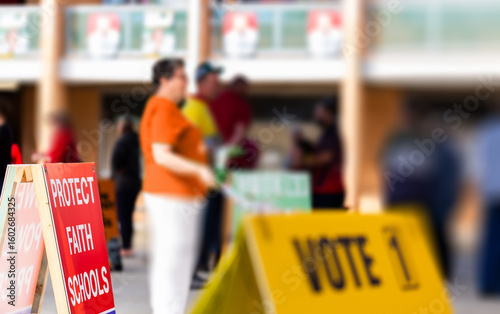 political sign with out of focus voters waiting to enter polling station