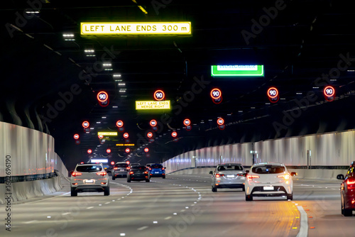 View from a car, Sydney toll road tunnel showing speed signs and four lanes with camera shake
