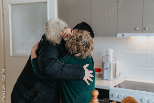 Fotografia A touching scene of an elderly lady sharing a warm hug with a loved one inside a modern kitchen, evoking love and togetherness