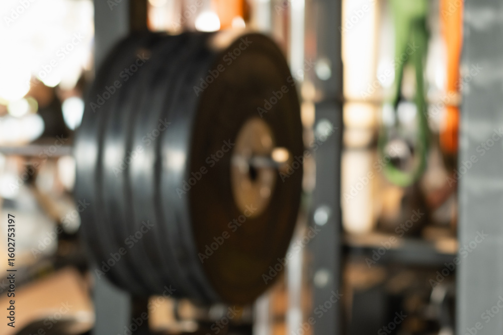 Obraz premium Abstract blurred gym background with sports fitness equipment barbell and weight plates in defocus. Sport background with space for design.
