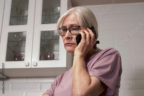 A Concerned Senior Woman on the Phone Portraying Emotion and Connectivity in a Modern Kitchen Environment
