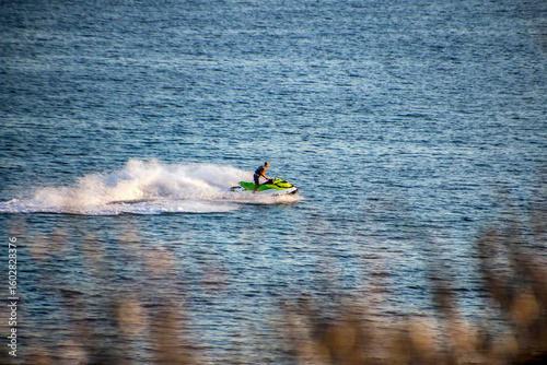 Fototapeta Naklejka Na Ścianę i Meble -  A man speeds along the sea on a jet ski