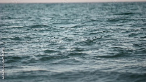 Slow motion recording of ocean swell at sunset with compressed wave layers from a telephoto perspective.