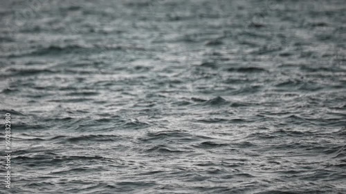 Rough sea captured at sunset in slow motion with telephoto lens creating compressed wave effect and warm tones.