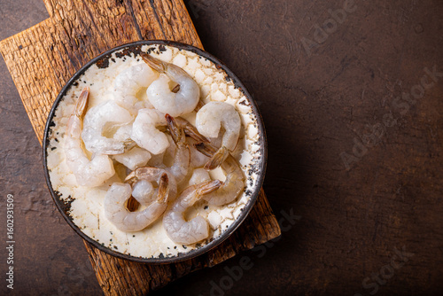 Fototapeta Naklejka Na Ścianę i Meble -   Raw shrimps in a plate on the dark background top view copy space for text