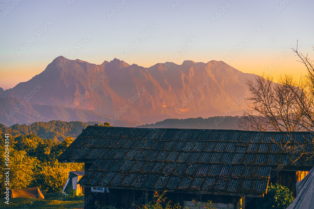 Obraz premium High-angle view of a beautiful orange, pink, and yellow sky in the evening as the sun sets. There is a view of Doi Luang Chiang Dao Mountain in the center of the image, which has a unique shape.