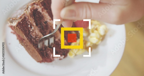 Cutting chocolate cake slice with fork on tabletop with scrambled eggs and focus reticle