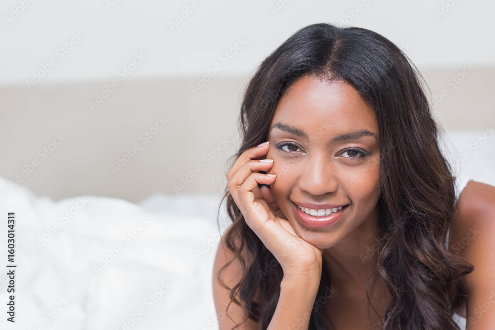 African American woman reclining on bed at home wearing sleeveless top with bedding, copy space African American woman reclining on bed at home wearing sleeveless top with bedding, copy space