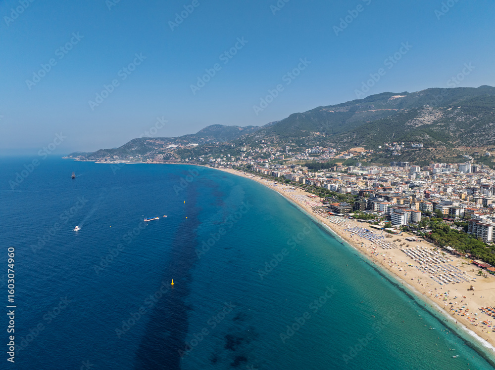 Fototapeta premium Aerial drone view of Cleopatra Beach in Alanya, Turkey. Alanya turquoise sea, sandy beach, cliffs, hills with caves, and the coastline during sunny summer day from above. Summer Mediterranean Sea.