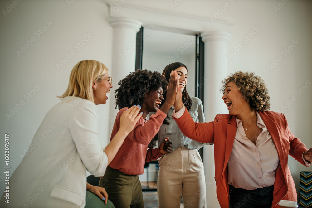 Obraz premium Enthusiastic businesswomen celebrating success with high five in office