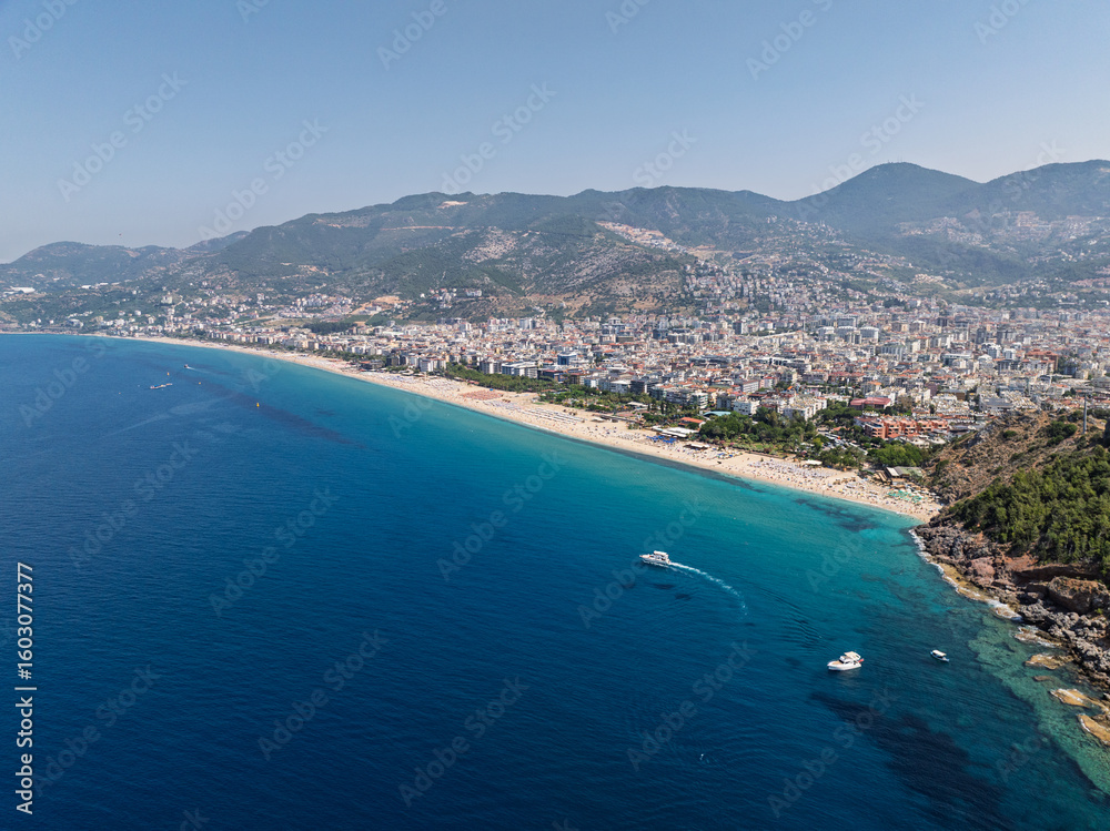 Fototapeta premium Aerial drone view of Cleopatra Beach in Alanya, Turkey. Alanya turquoise sea, sandy beach, cliffs, hills with caves, and the coastline during sunny summer day from above. Summer Mediterranean Sea.