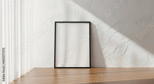 Empty rectangular picture frame with black border leaning against a textured wall with natural light and shadows