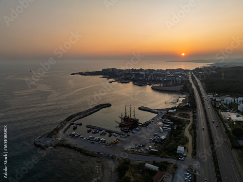 Fototapeta Naklejka Na Ścianę i Meble -  Stunning aerial sunset to night transition over Turkler in Alanya, Turkey. Alanya coastline,resorts,marina,hotels and city lights along the Mediterranean Sea drone view. Mediterranean Sea coastline.