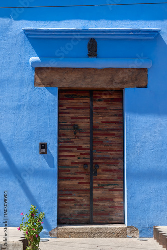 Entrance with a blue wall and a wooden door in Oaxaca, Mexico