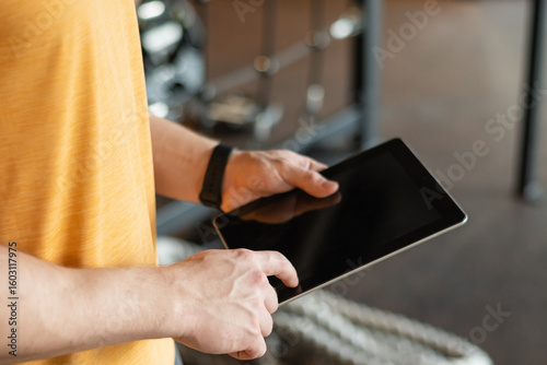 Personal trainer or sporty man holding tablet at gym or fitness center. Check workout plan. Trainer making exercise plan.