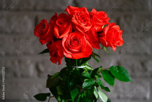 Bunch of orange roses with green leaves on a blurred background in the living room