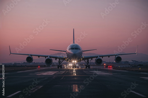 Airplane on runway at dusk with lights on