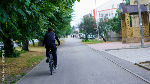 Wallpaper Mural Bicyclist rides along a tree-lined street in a quiet neighborhood during late afternoon hours Torontodigital.ca