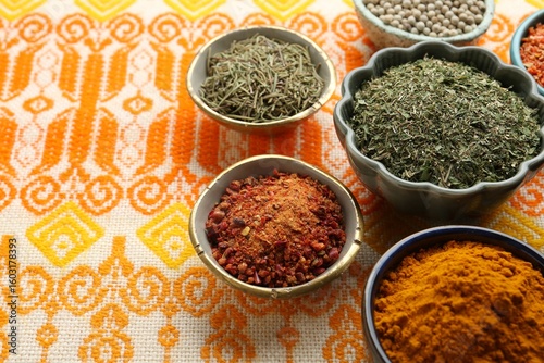 Fototapeta Naklejka Na Ścianę i Meble -  Many different aromatic spices in bowls on table with cloth, closeup. Space for text