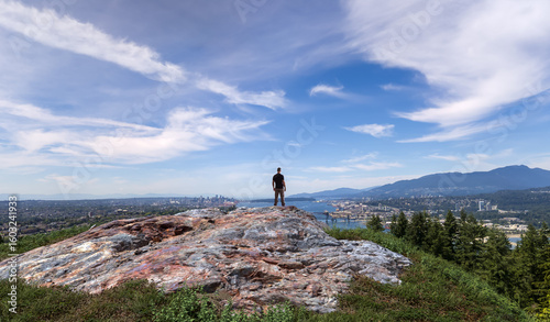 Lone Person Standing On Rock Overlooking Cityscape With Vast Blue Sky