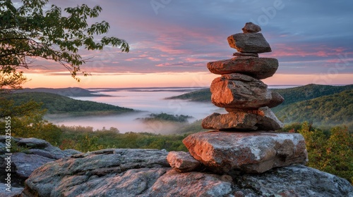 A serene mountain vista at sunrise with a balanced rock cairn.