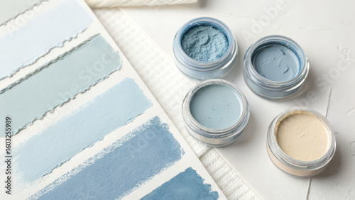 Collection of soft blue and cream pigment jars and fabric swatches isolated on transparent background