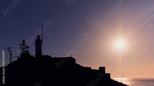 Backlight of a lighthouse with a sun in the background