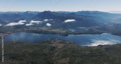 Lake Ñorquinco nestled amidst rolling, forested hills with distant mountain ranges of Los Andes, Patagonia, Argentina